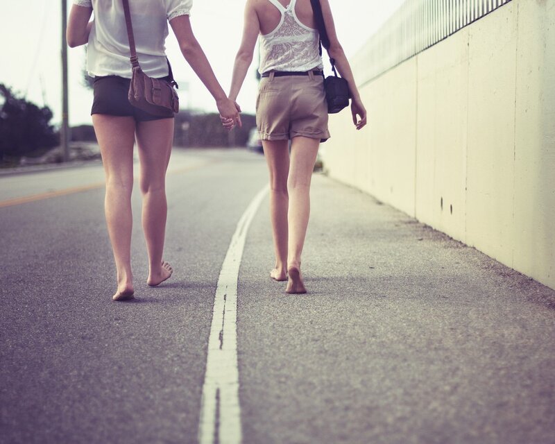 Two women walking barefoot on a road
