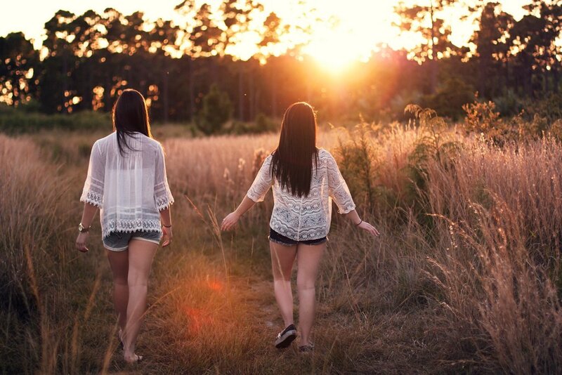 Two women walking in a field at sunset