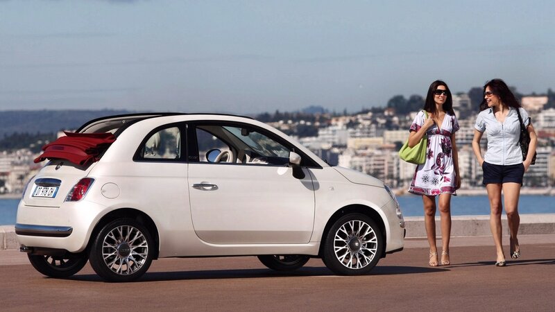 Two women walking near a white car