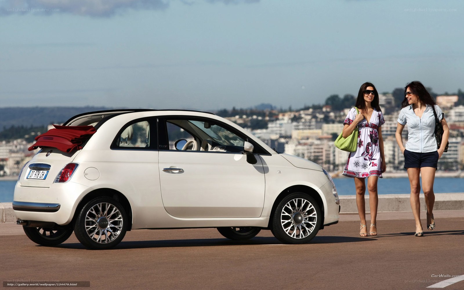 Two women walking near a white car