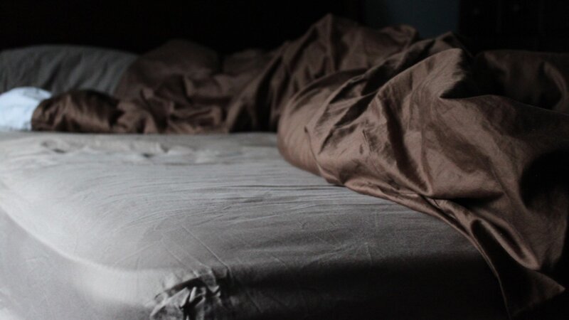 unmade bed in dim light