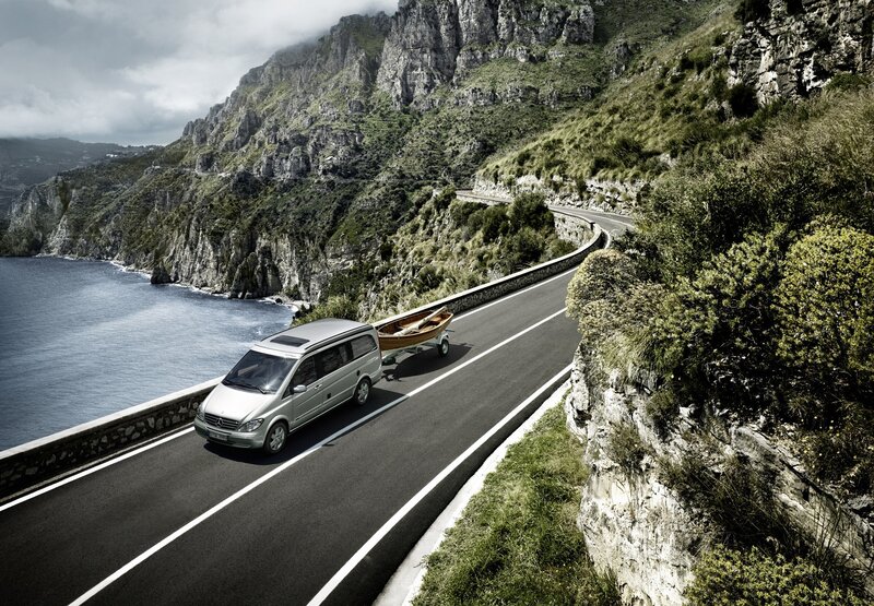 Van on coastal road with boat