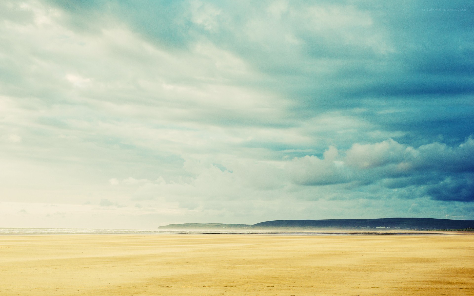 Vast beach under cloudy sky