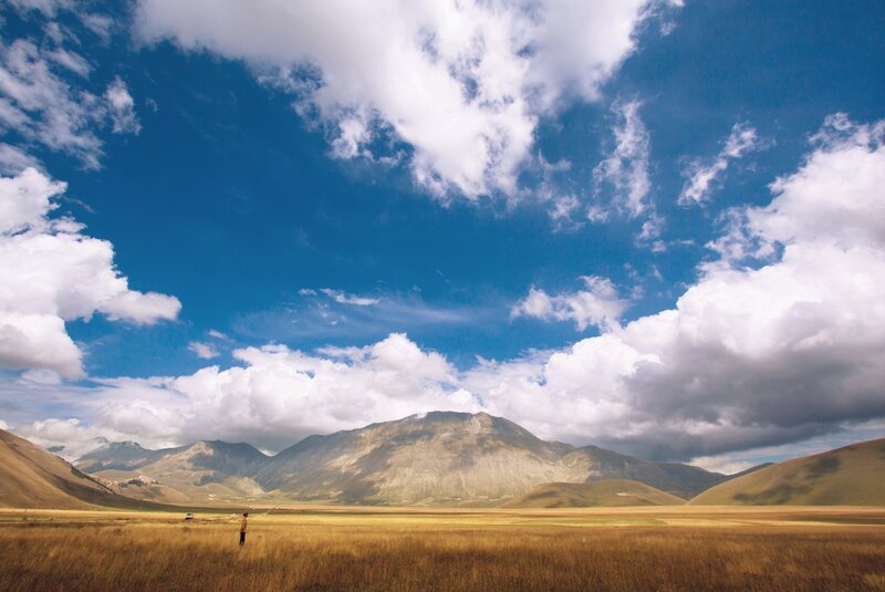 Vast field with mountains and clouds