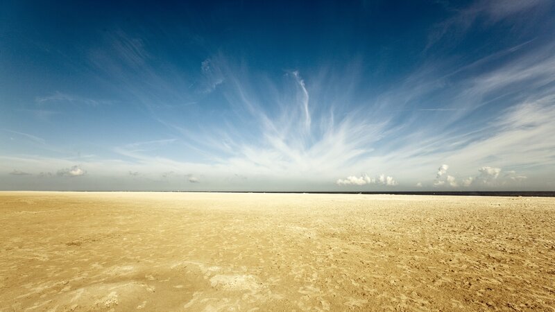 Vast sandy beach under blue sky