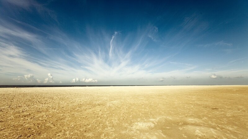 Vast sandy beach under blue sky