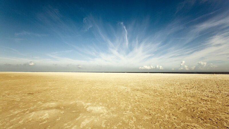 Vast sandy beach under blue sky