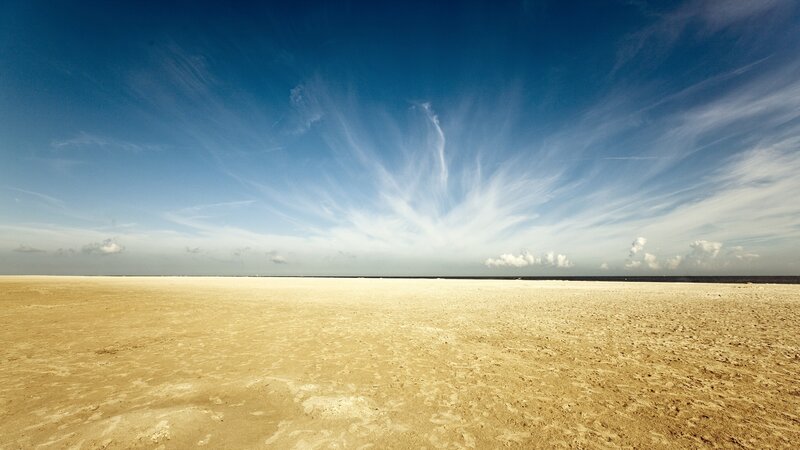Vast sandy beach under blue sky