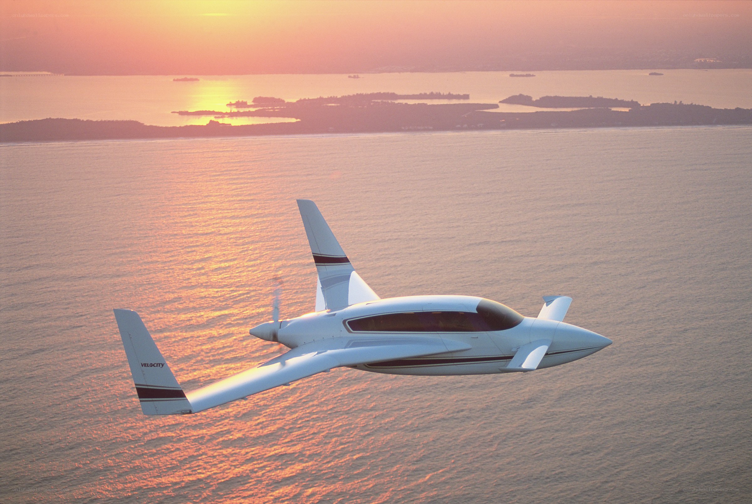 Velocity aircraft over water at sunset