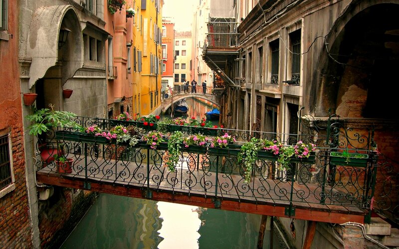 Venetian canal with flower-decorated bridge