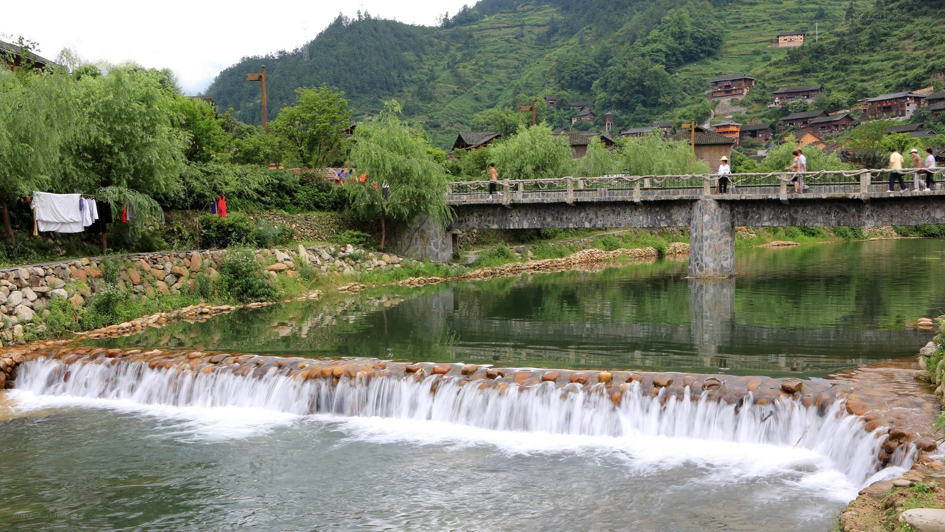 village by a river with waterfall
