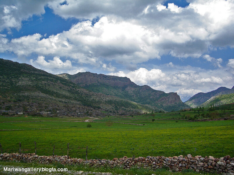 Village in Mountain Valley — Green, Serene, Afternoon, Photograph, Mountains, Fields, Clouds