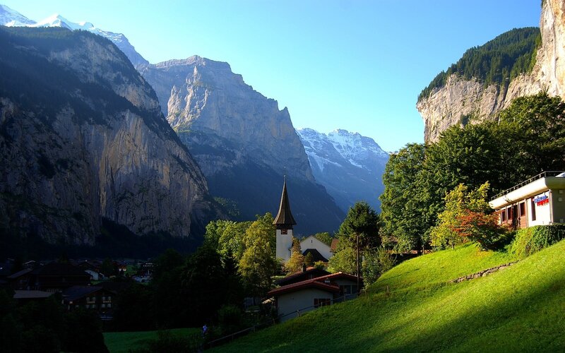 Village in Mountain Valley — Green, Serene, Morning, Photograph, Church Steeple, Snow-capped Peaks