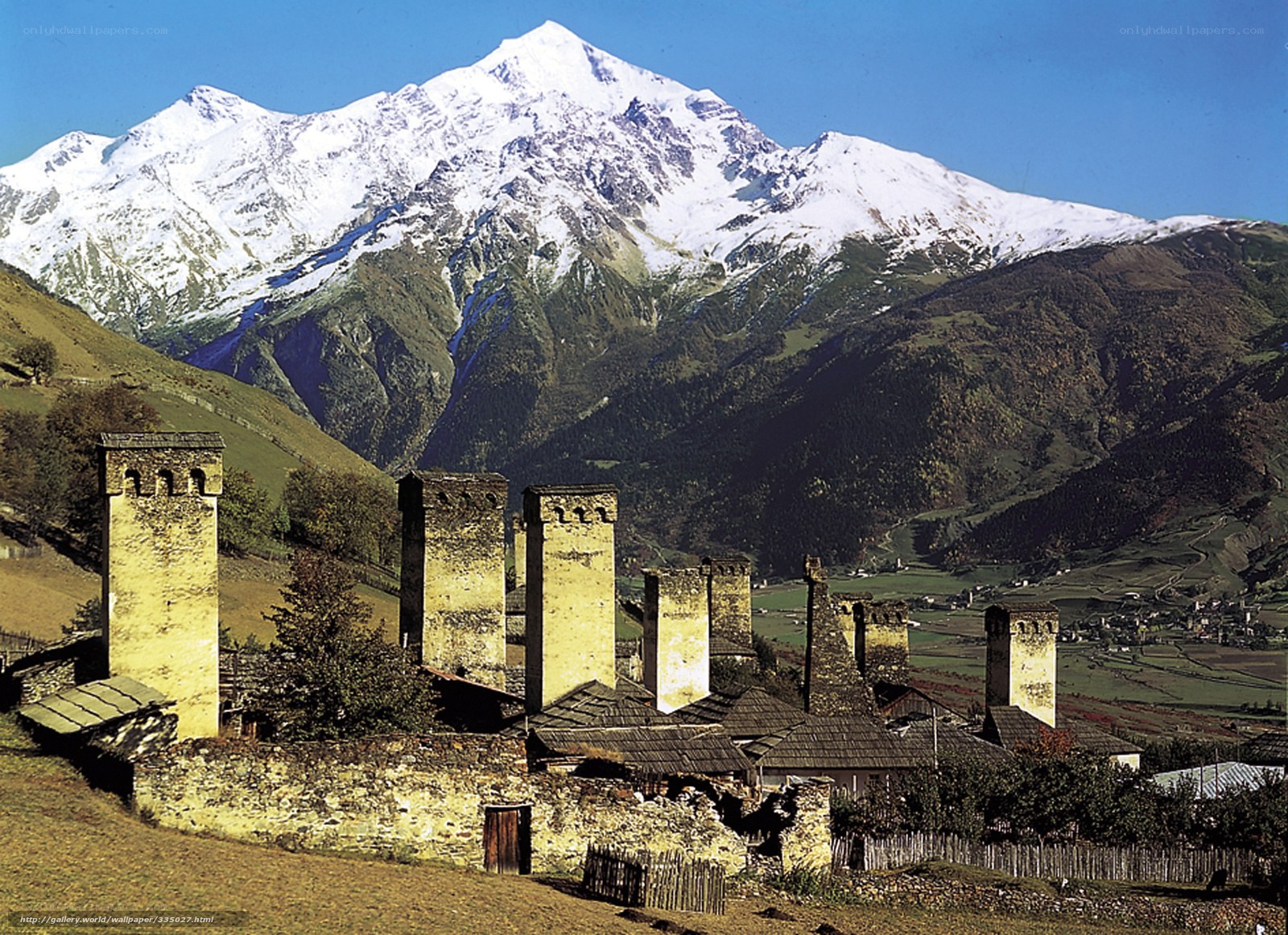 Village with stone towers and snow-capped mountains