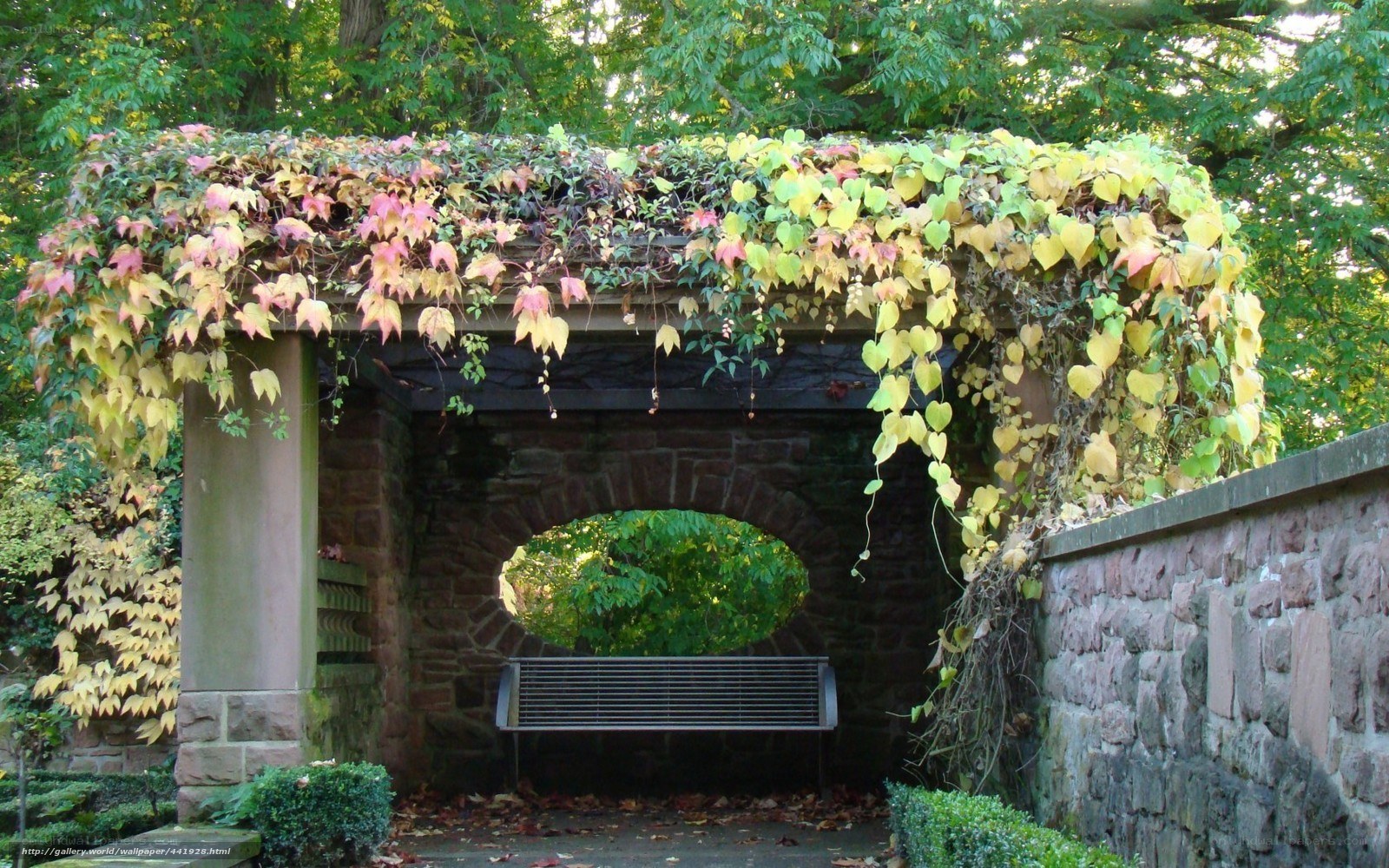 Vine-covered stone archway with bench