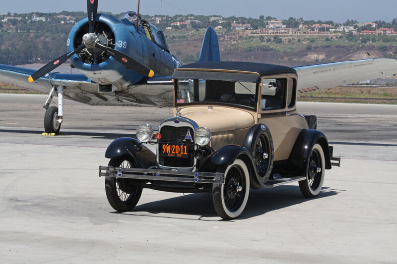 Vintage car and warplane on tarmac