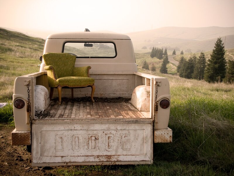 Vintage truck with armchair in field