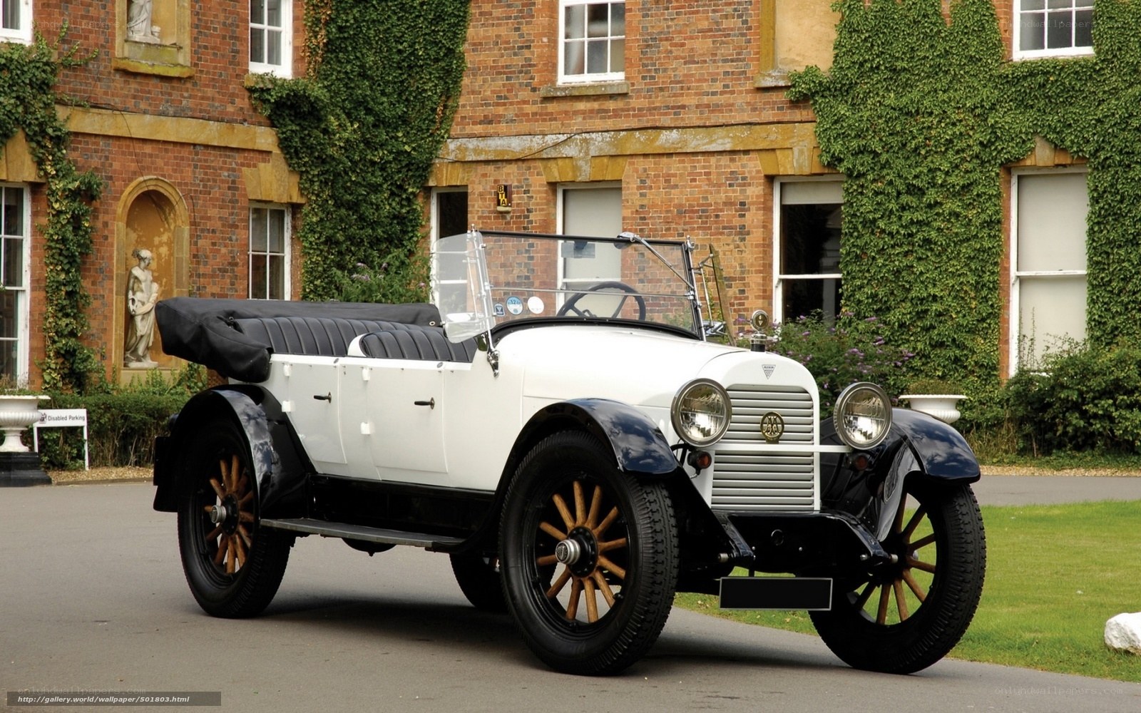 Vintage white car in front of brick building