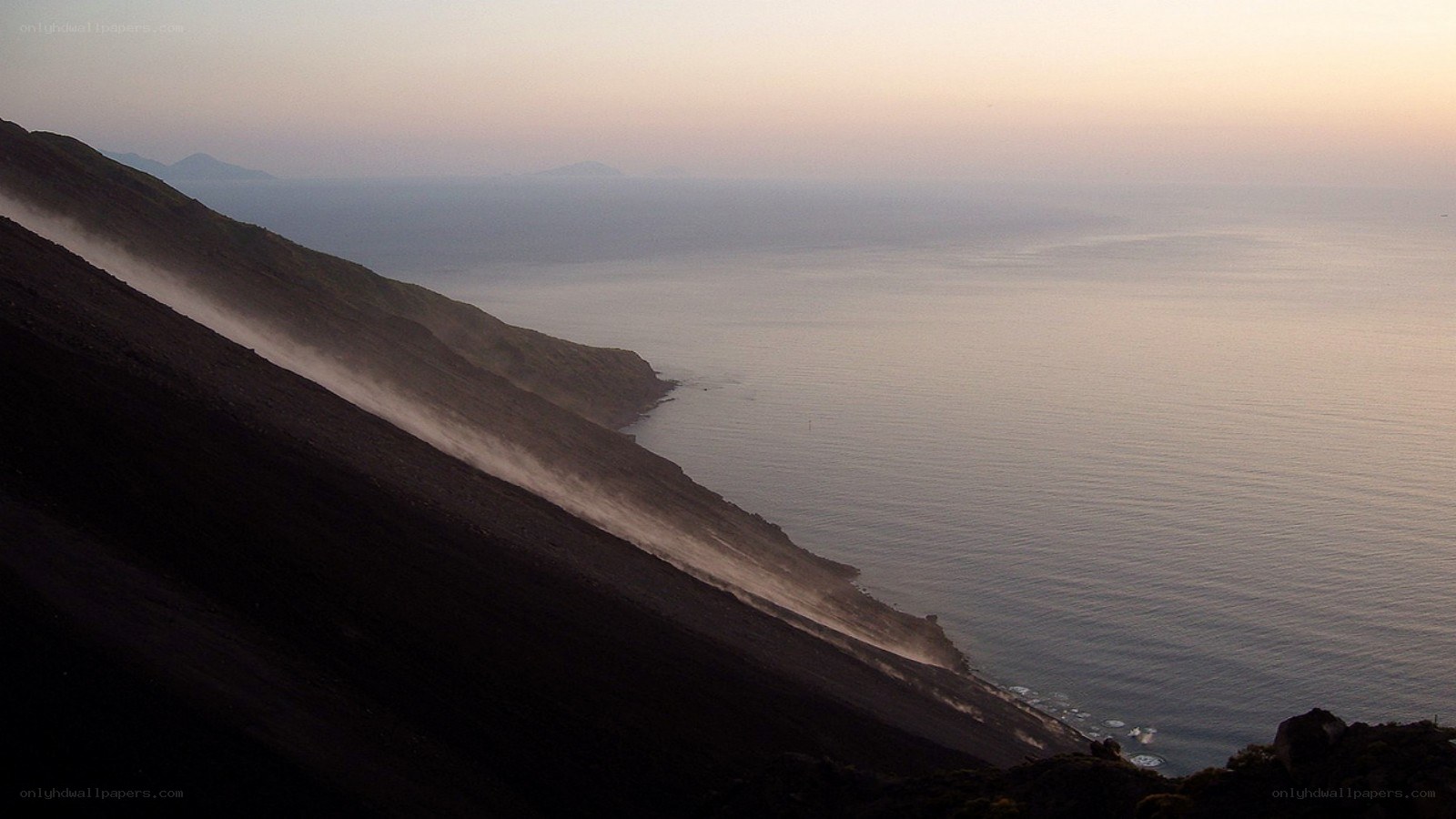 Volcanic slope meets ocean at dusk