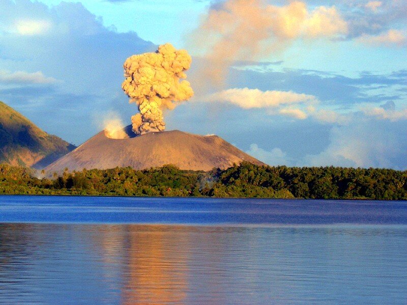Volcano erupting by a lake