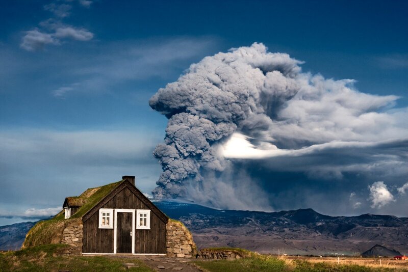 Volcano erupting near a turf house