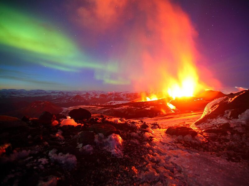 Volcano erupting under aurora