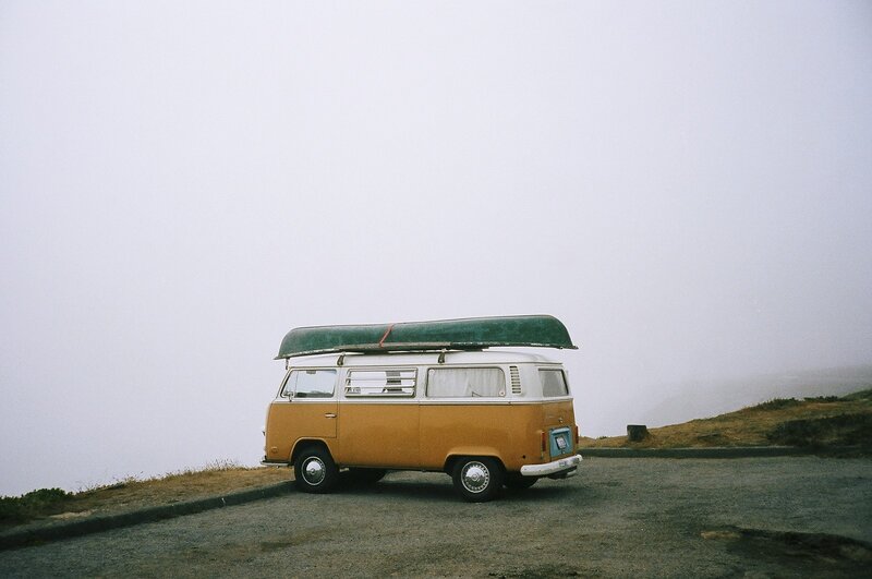 VW van with canoe on foggy cliff