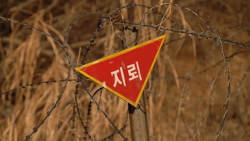 Warning sign on barbed wire fence