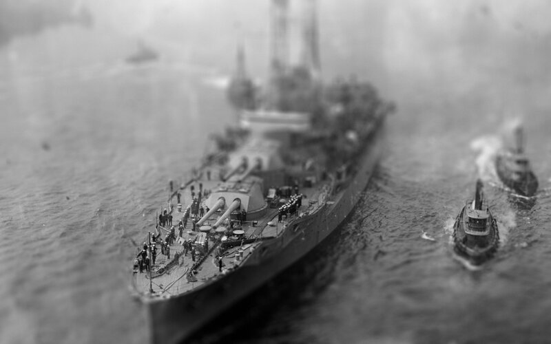 Warship at sea with tugs