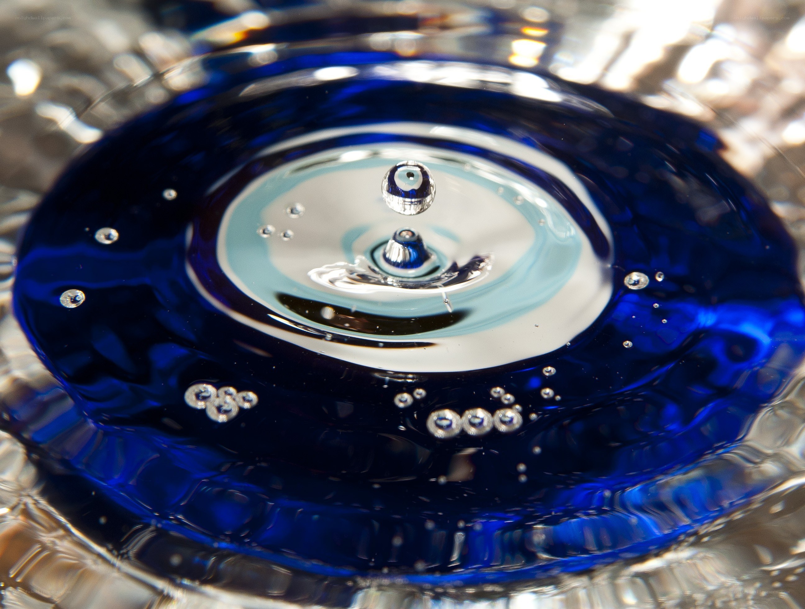 Water drop impact in blue liquid