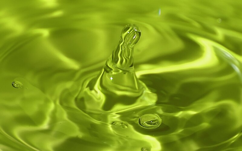 Water drop impact in green liquid