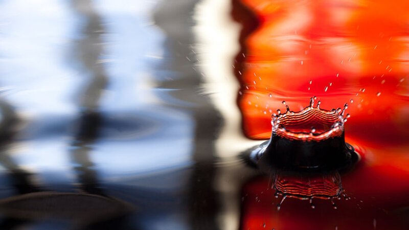 Water drop splash in red liquid