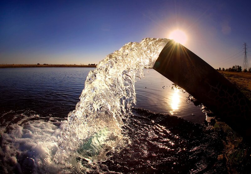 Water flowing from a pipe at sunset