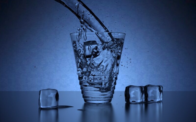 Water pouring into glass with ice