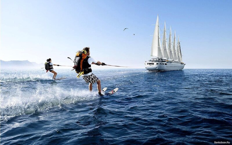 Water skiing near a sailboat