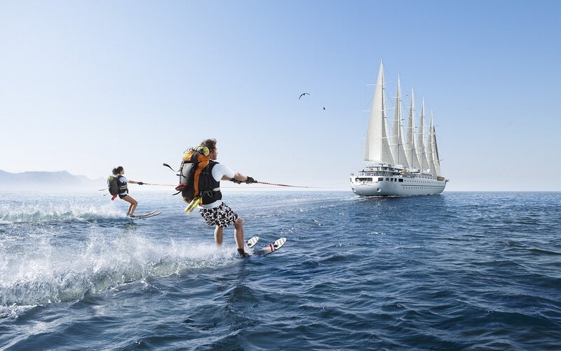 Water skiing near a sailboat