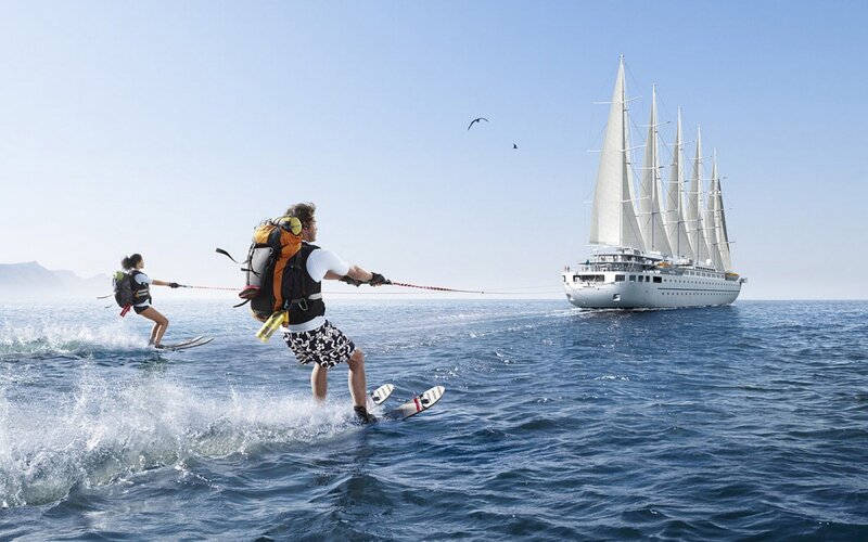 Water skiing near a sailing ship