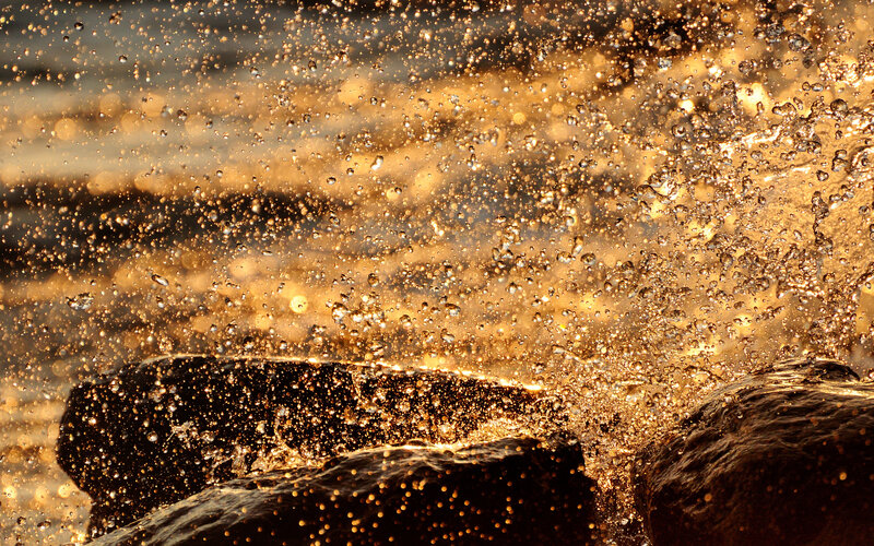 Water splashing on rocks at sunset