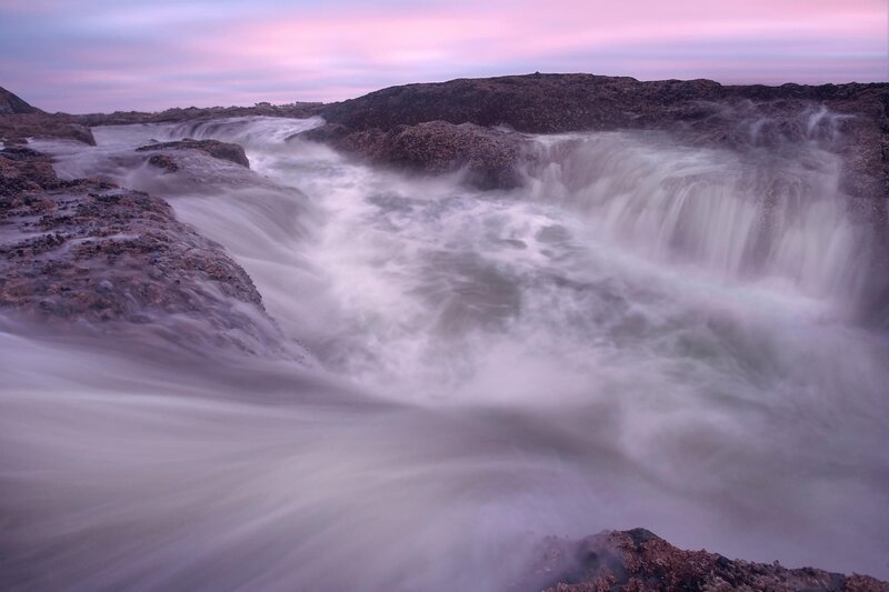 Waterfall at dusk on rocky coast