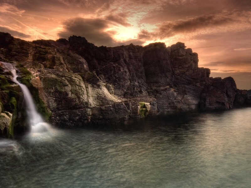 Waterfall at sunset on rocky coast