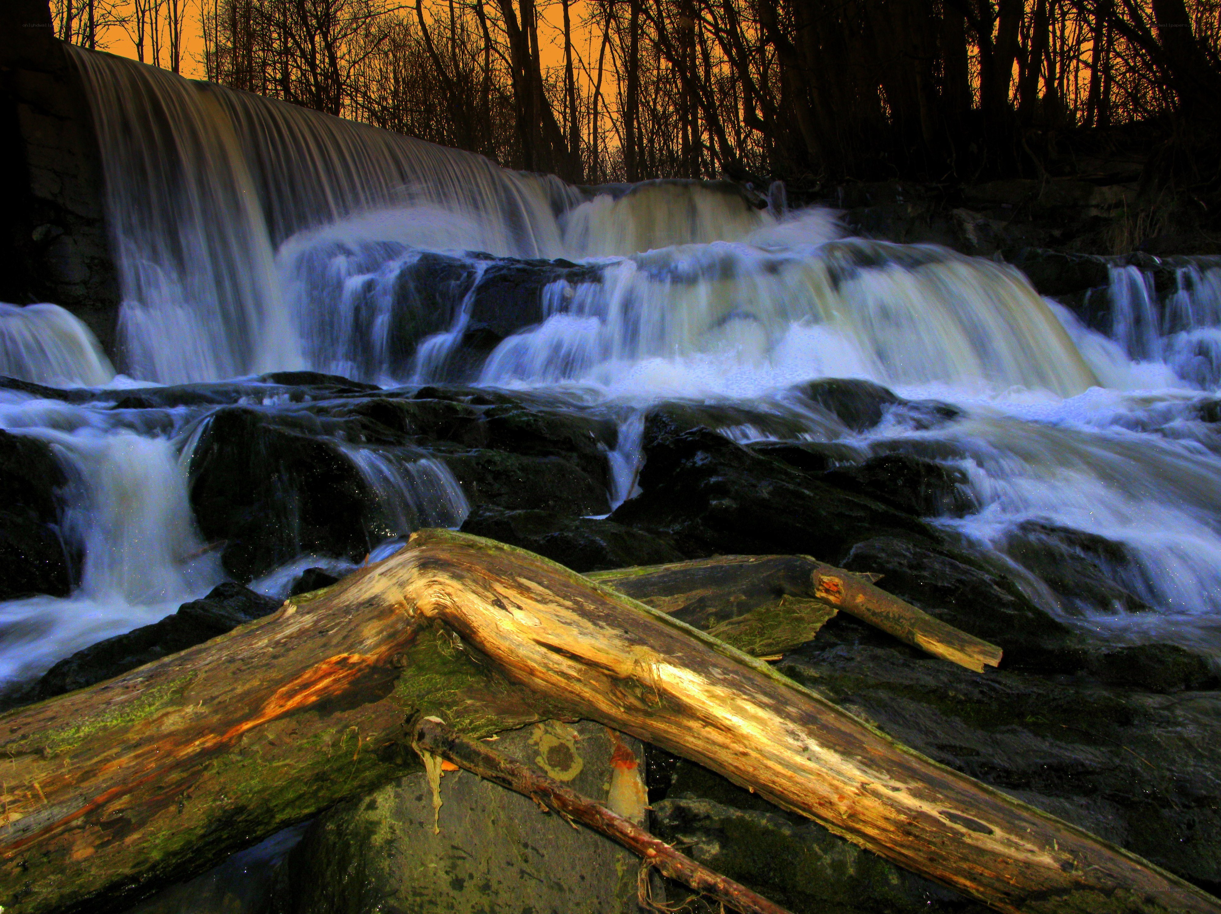 Waterfall at sunset with fallen log