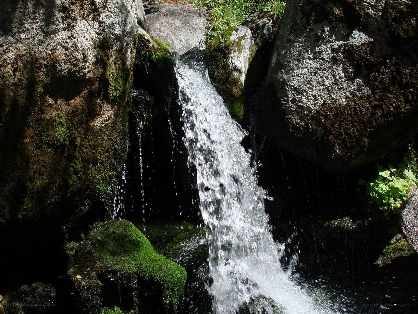Waterfall between mossy rocks