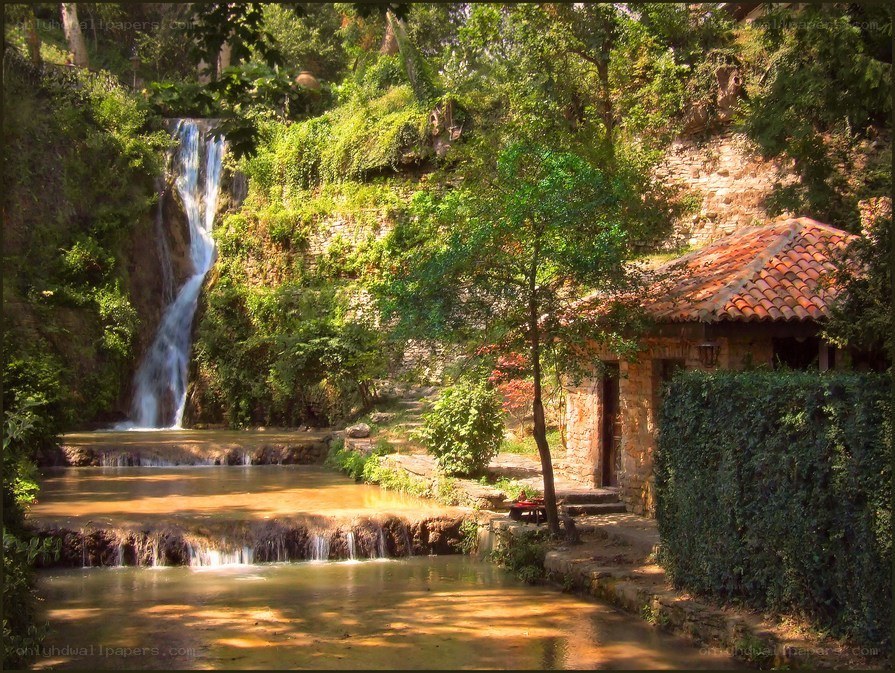 Waterfall by stone cottage