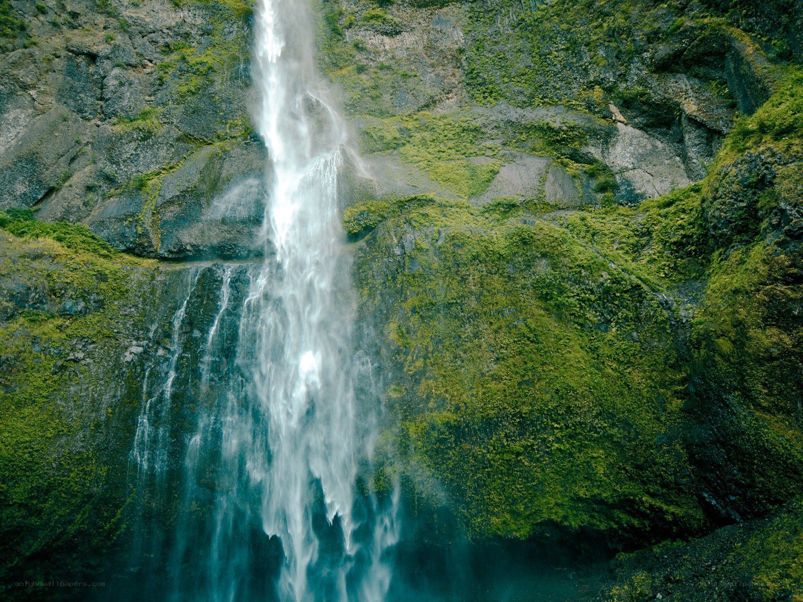 Waterfall cascading down mossy cliff
