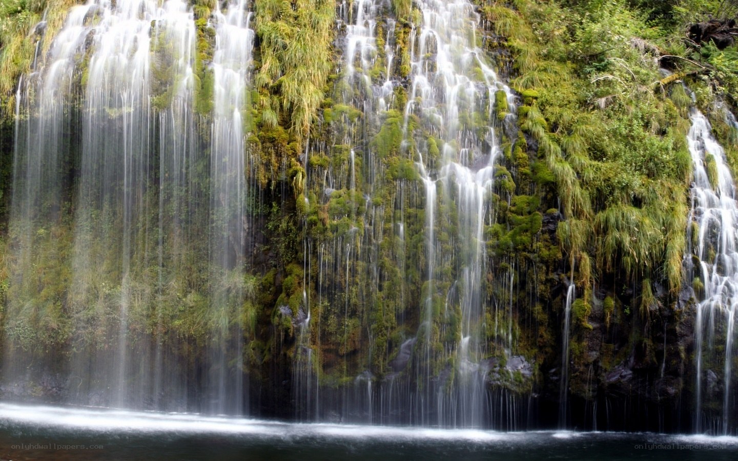 Waterfall cascading over mossy cliff