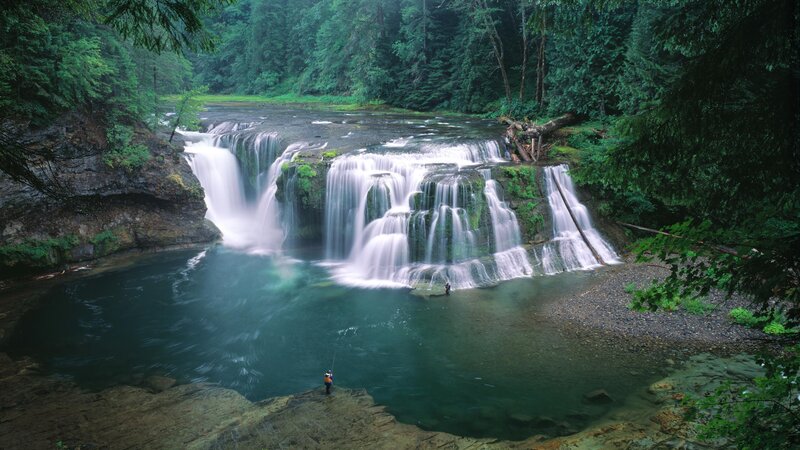 Waterfall in forest with fisherman