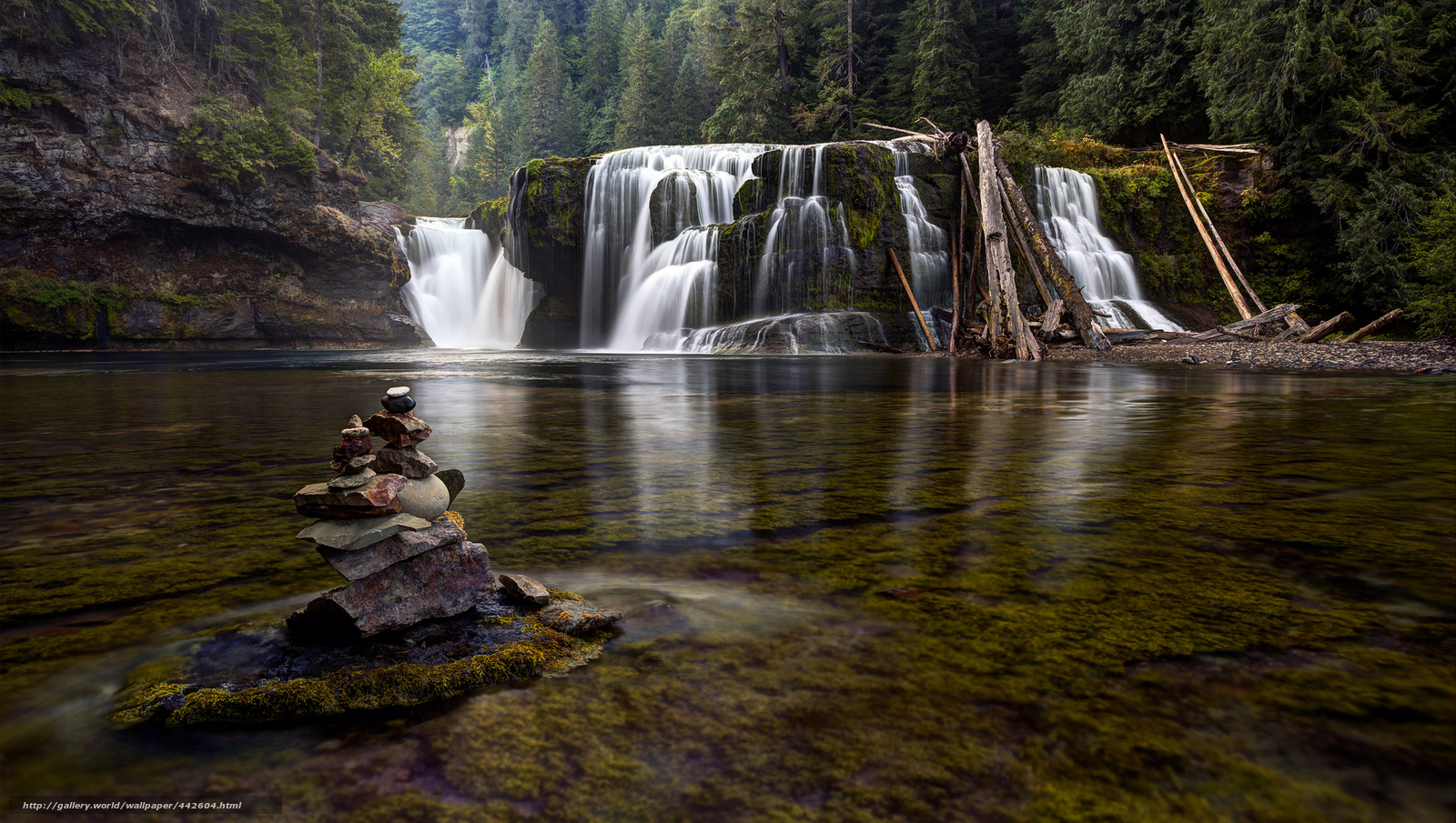 Waterfall in forest with stone cairn
