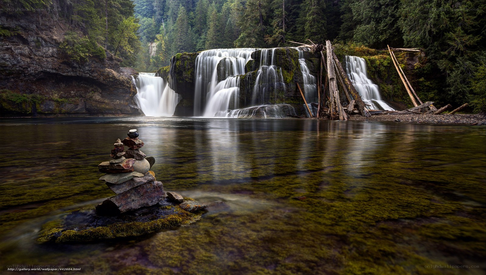 Waterfall in forest with stone cairn