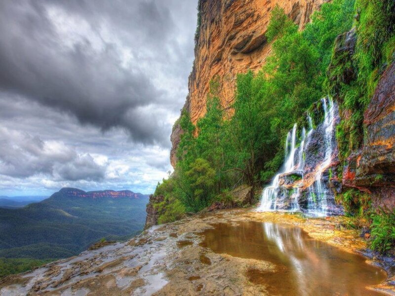 Waterfall on Cliff Face — Green, Dramatic, Photograph, Trees, Clouds