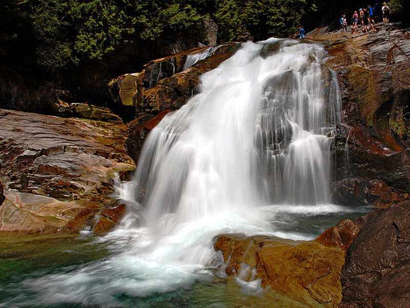 Waterfall on Rocky Cliff — Green, Serene, Afternoon, Photograph, People